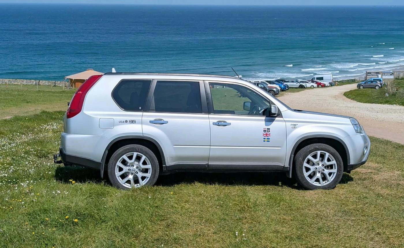 PHD Taxi Services' silver Nissan X-Trail parked above the sea in Cornwall